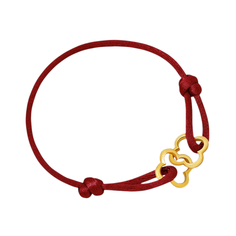 Aureliss geflochtenes Armband in Dunkelrot mit einem filigranen, goldfarbenen Kleeblatt-Anhänger aus Metall.