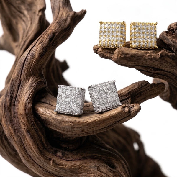 Aureliss quadratische Ohrstecker mit funkelnden Zirkonia-Steinen in Gold und Silber auf einem dekorativen Holzstück