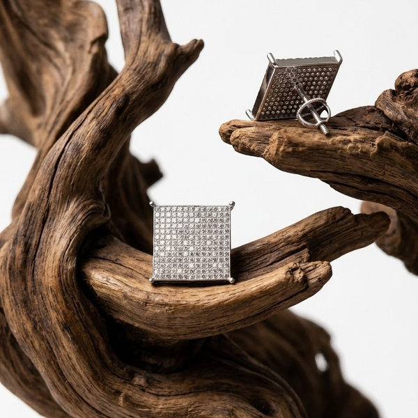 Aureliss quadratische Ohrstecker in Silber mit funkelnden Zirkonia-Steinen auf einem dekorativen Holzstück präsentiert.
