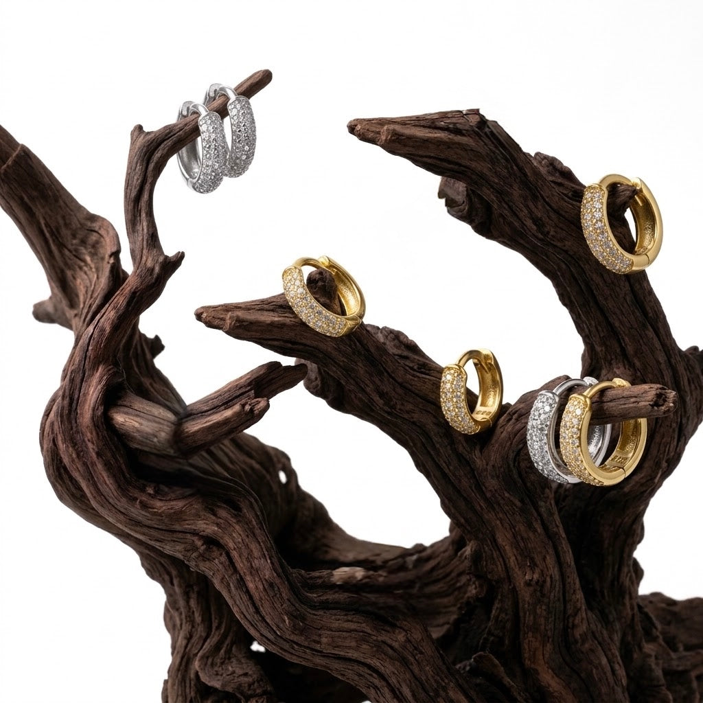 Aureliss Zane Creolen aus 925er Sterlingsilber und Gold mit Zirkonia-Steinen auf einem dekorativen Holzstamm präsentiert